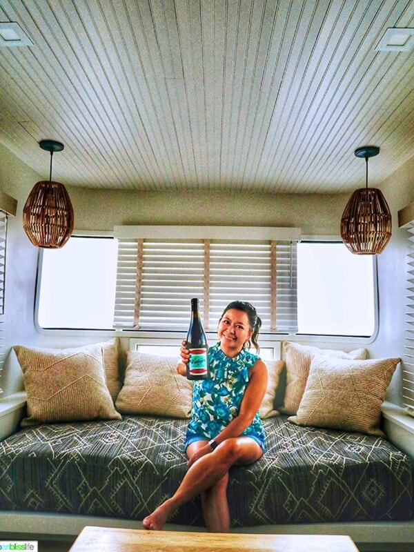 Marlynn Schotland holding up a bottle of wine inside the mansion airstream at Vintages Trailer Resort