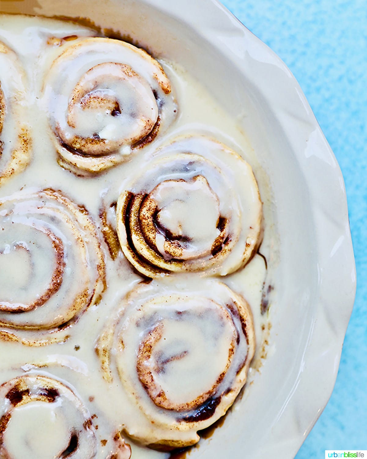 half baking pan of orange cinnamon rolls with icing.