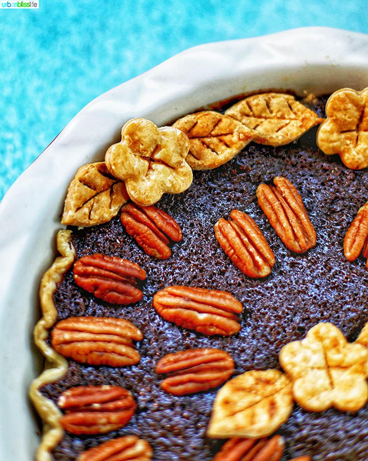 corner of Chocolate Bourbon Pecan Pie closeup of decorative pie crust leaf and flower cutouts.