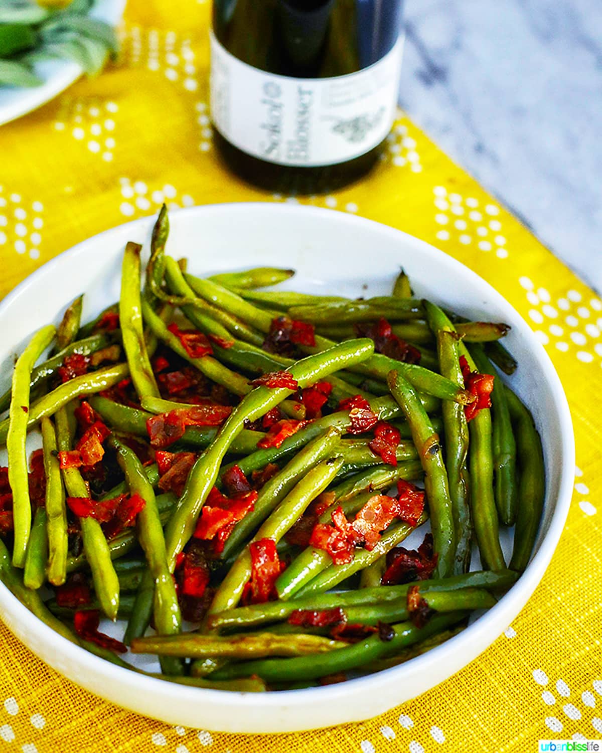 green beans with bacon with bottle of wine.