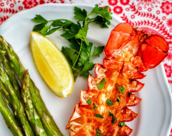 lobster tail with lemon, asparagus, white wine on red and white cloth