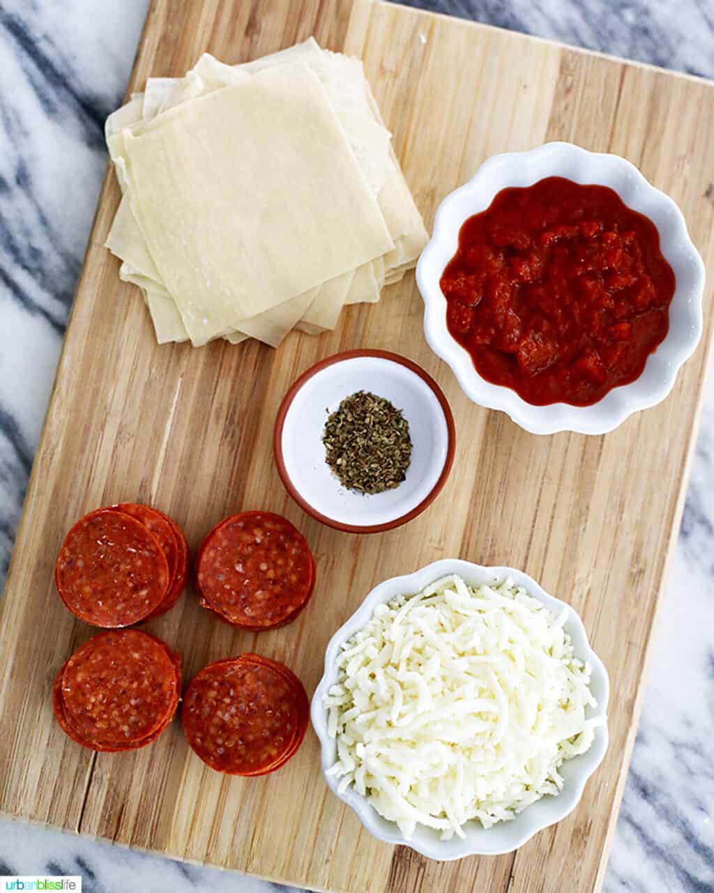 cheese pepperoni slices wonton wrappers pizza sauce on a cutting board ingredients for pizza rolls