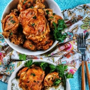two bowls of Instant Pot Filipino Chicken Adobo and rice, with a colorful floral napkin and forks.