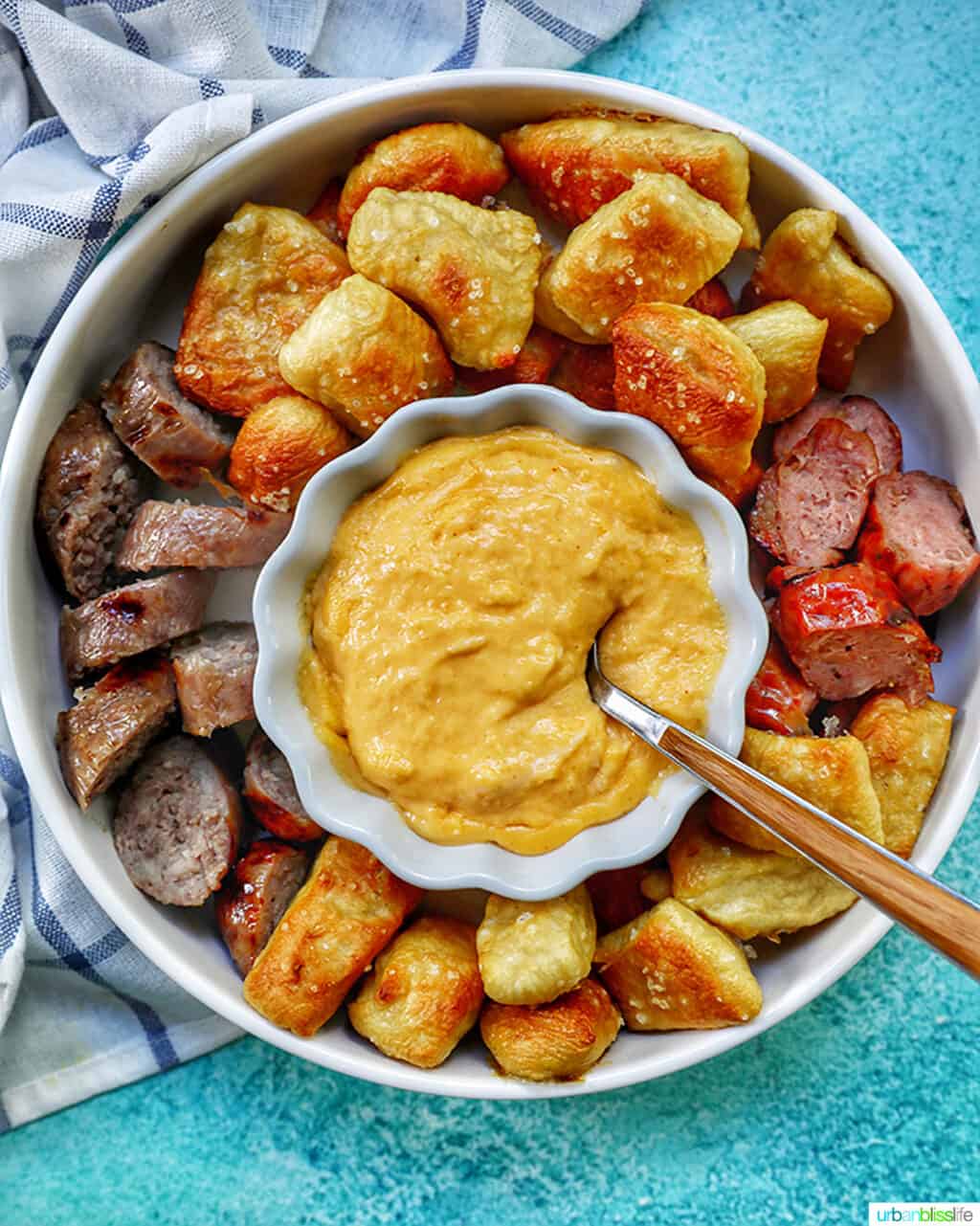 soft pretzel bites in a large bowl with cheese dip and sausages