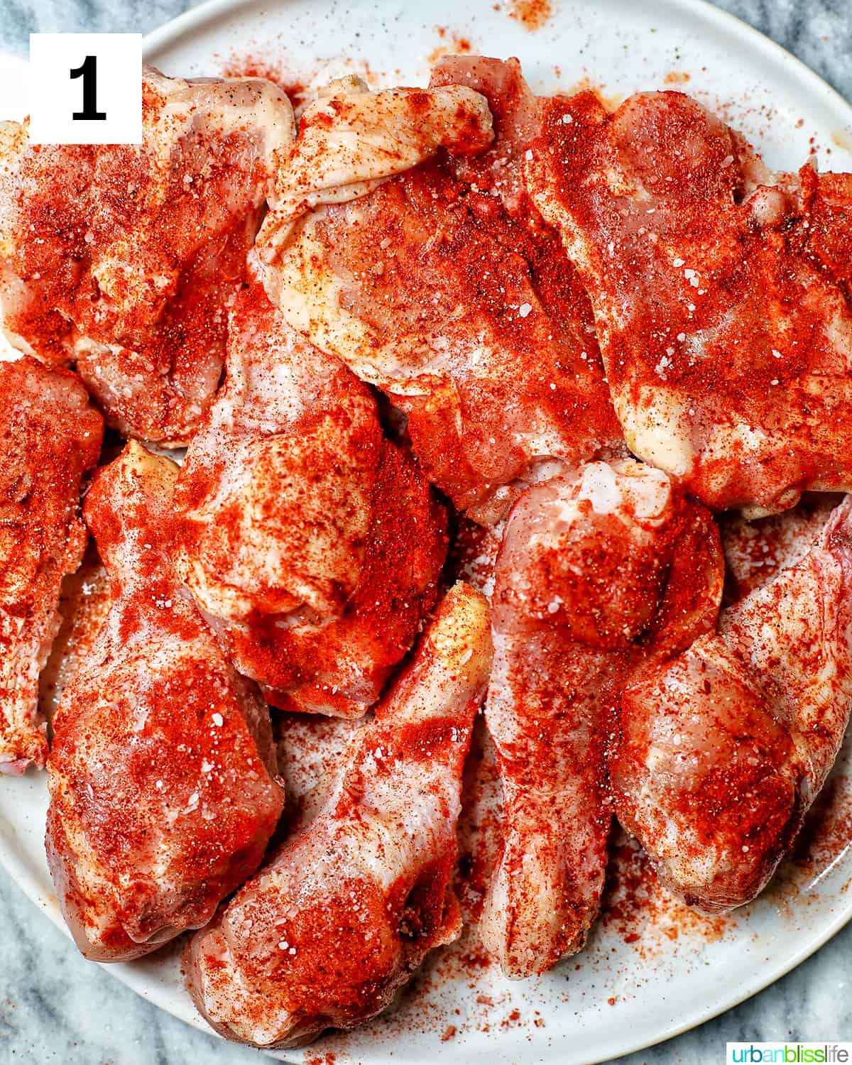plate with chicken pieces seasoned with paprika, salt, and pepper.