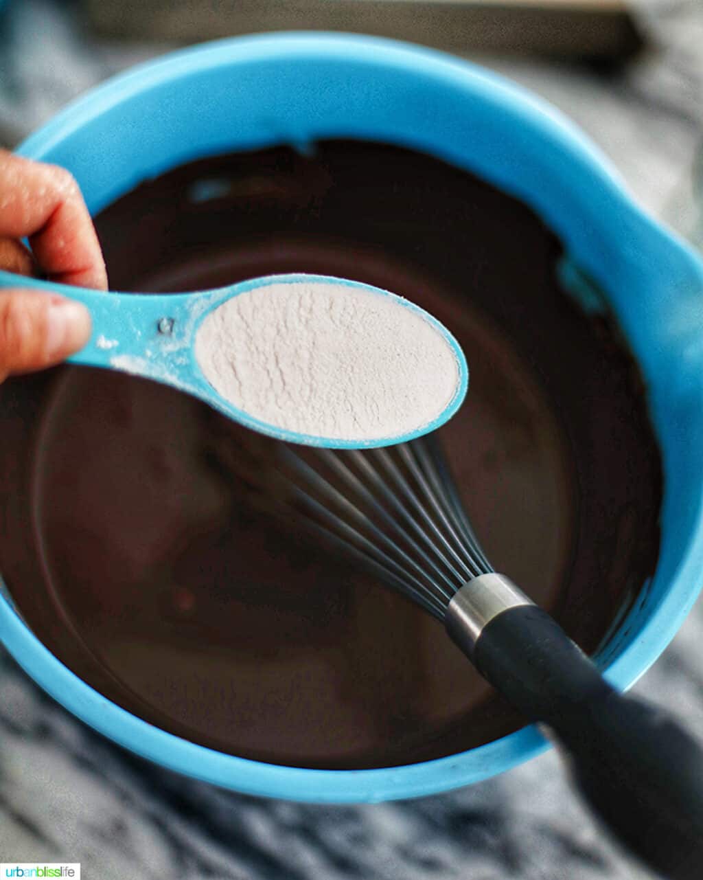 pouring flour into chocolate brownie mixture