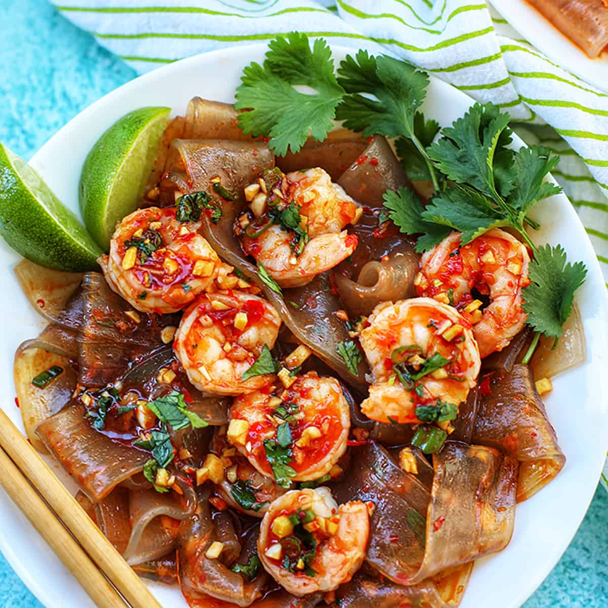 plate of wide glass noodles with shrimp and fresh herbs.