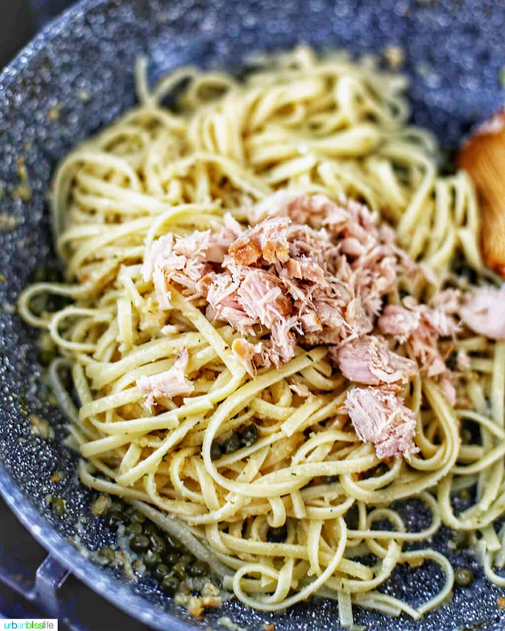 adding tuna to pasta in skillet