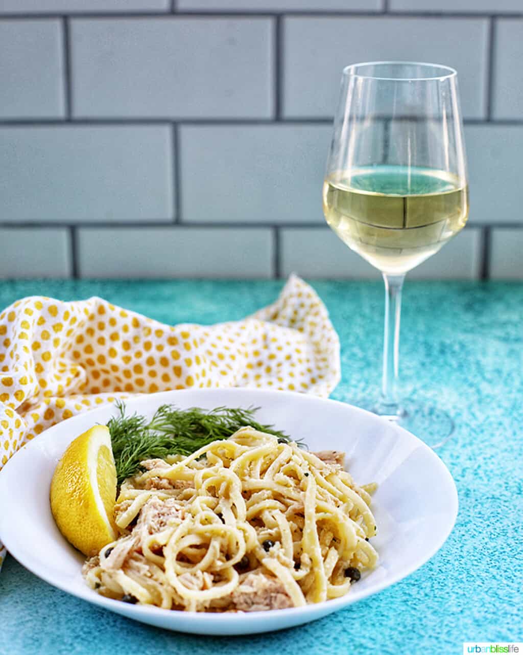 glass of white wine with bowl of tuna pasta