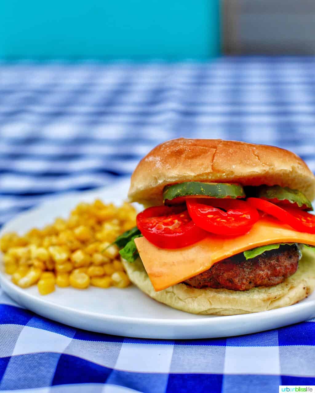 burger and side of corn on checkered tablecloth