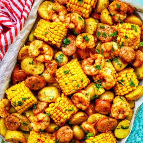 tray of seafood, corn, sausage low country boil with blue background and red and white towel