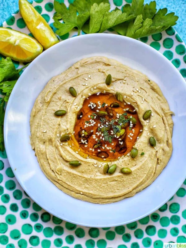 hummus in a white bowl on green polka dot platter with lemon slices