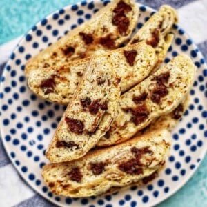 chocolate chip almond biscotti stacked on a polka dot plate.