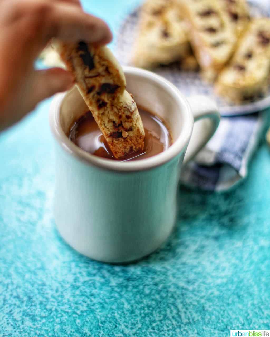 dunking chocolate chip almond biscotti into coffee