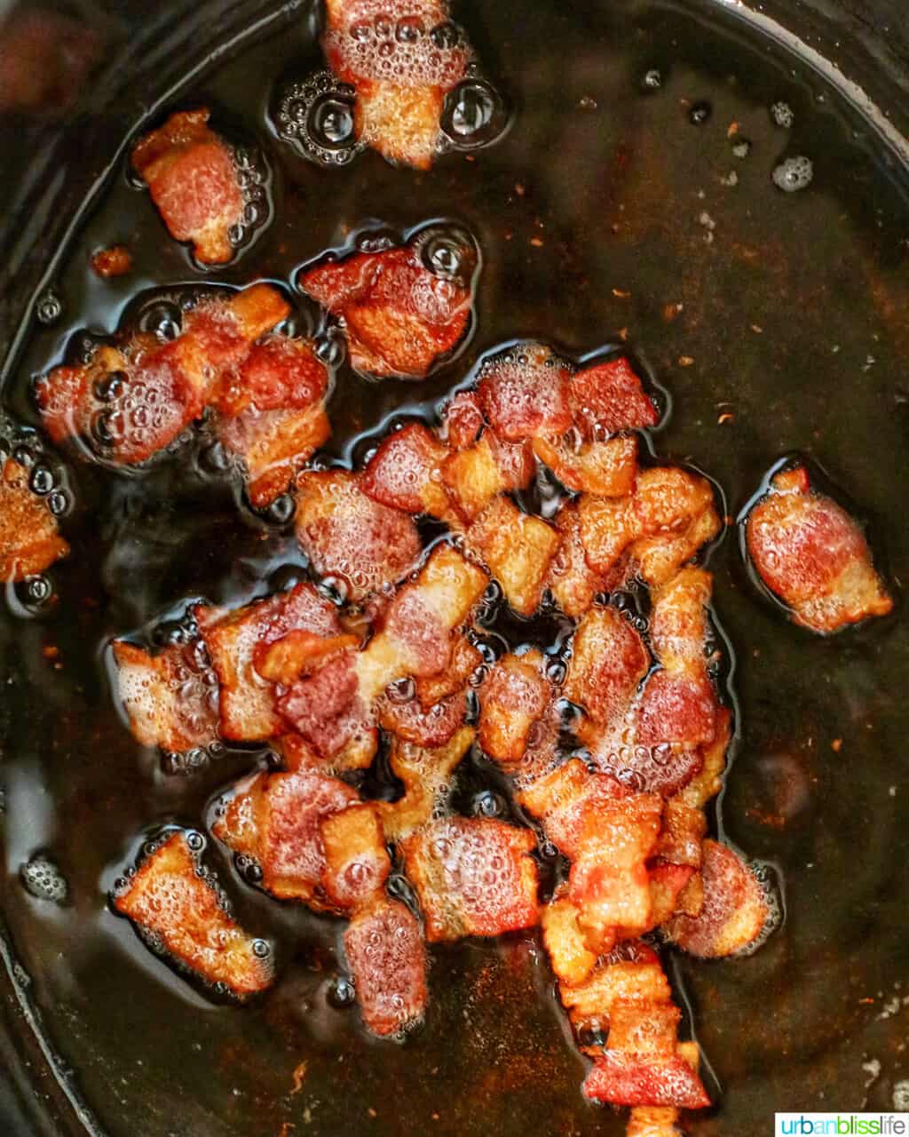 cooked bacon sizzling in Dutch oven