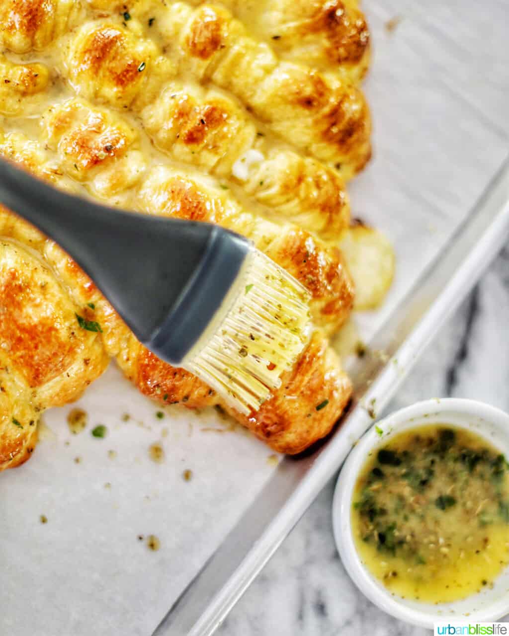 brushing butter herb mix onto dough