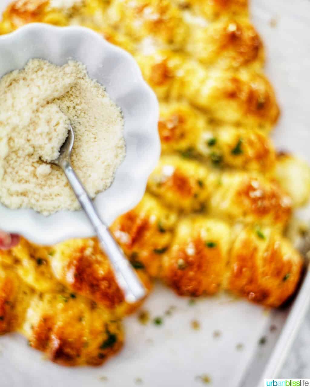 sprinkling parmesan cheese over Christmas Tree Pull-Apart Bread