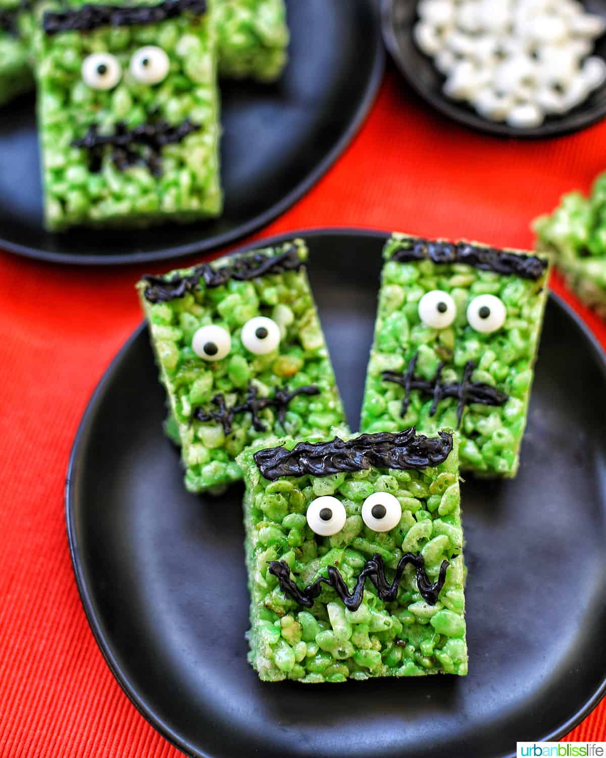 Frankenstein Rice Krispie Treats on top of black plates and orange background