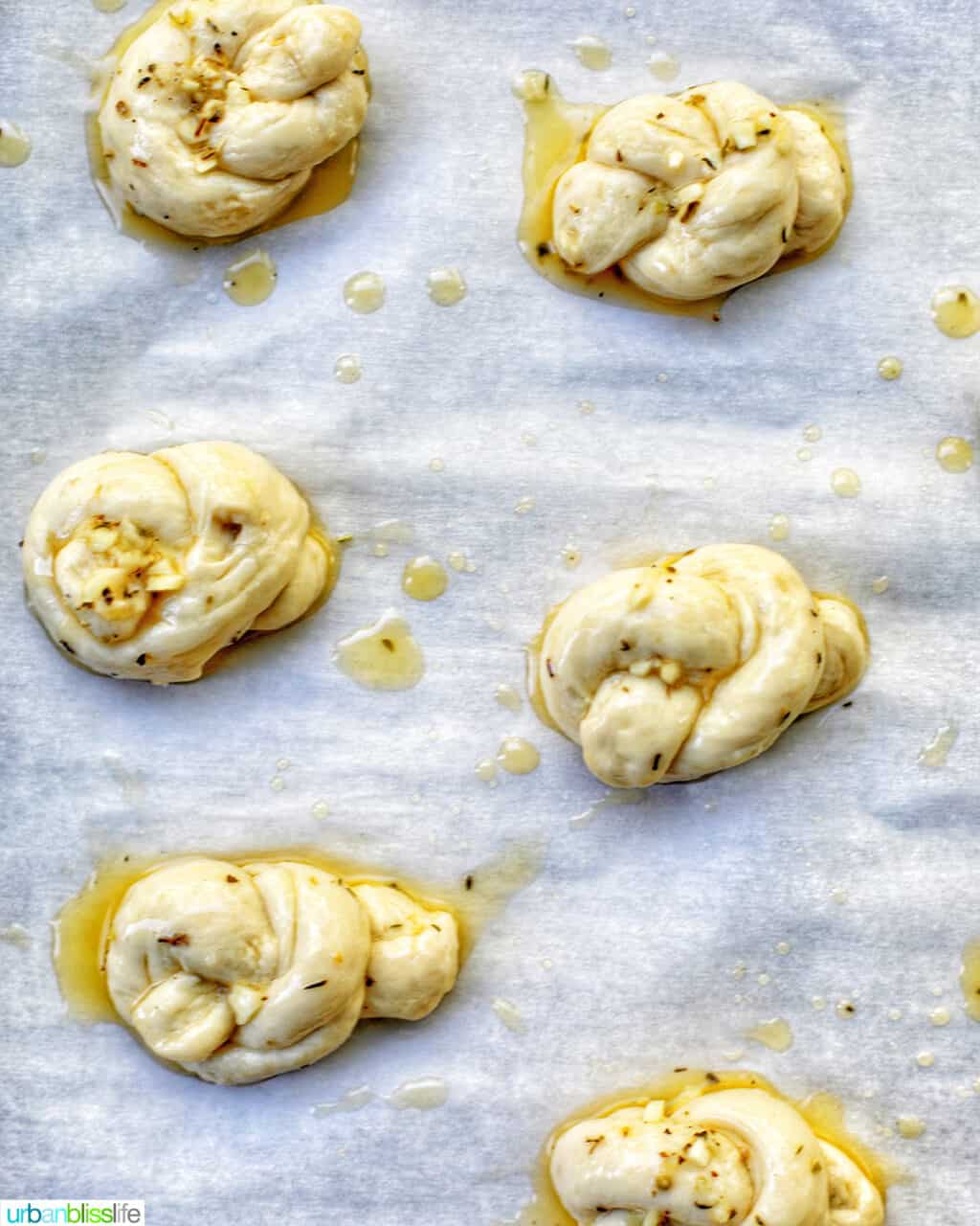 garlic parmesan knots with olive oil on a baking sheet