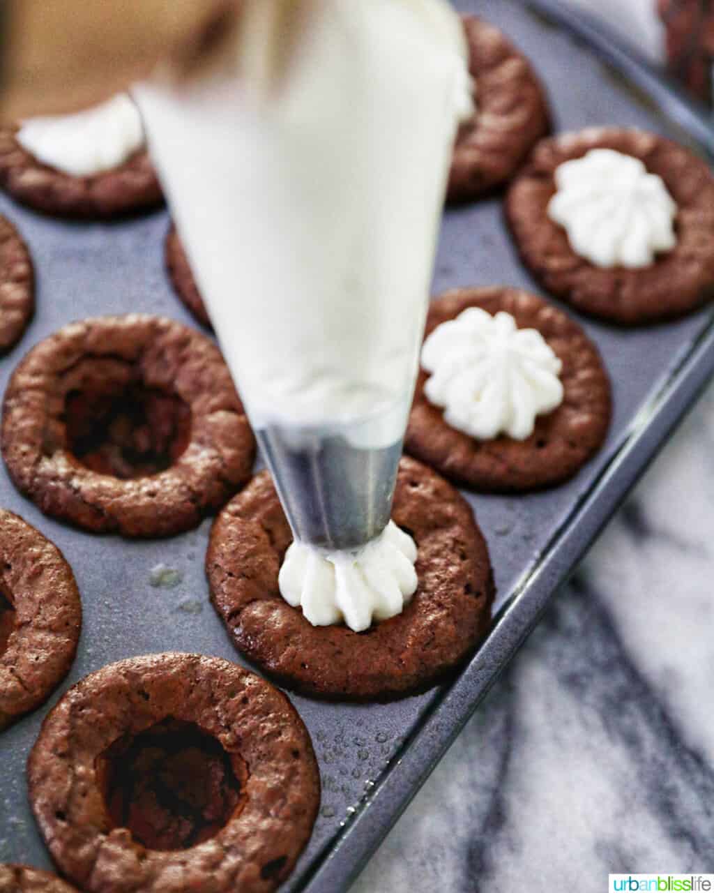 adding eggnog whipped cream to mini brownie bites