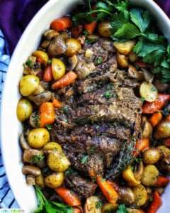 dutch oven pot roast with vegetables in a large white serving platter