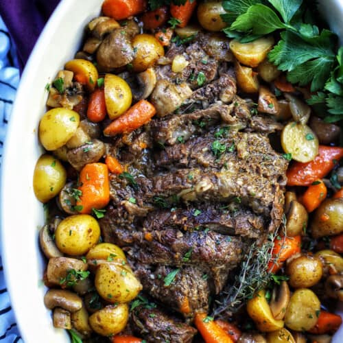 dutch oven pot roast with vegetables in a large white serving platter