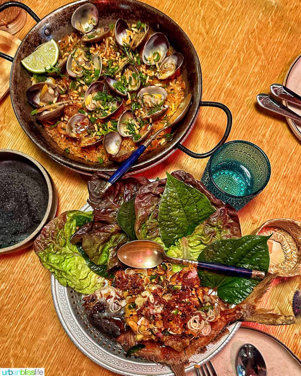 Plate of Thai Paella and plate of whole fried fish on wooden table at Phuket Cafe.