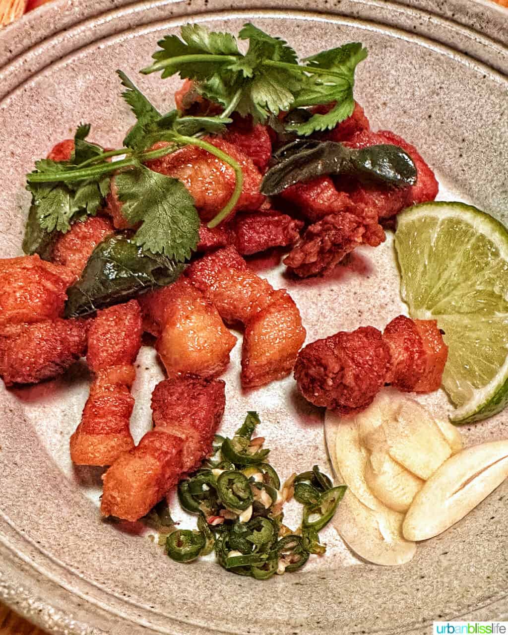 pork belly bites on a grey plate with lime wedge at Phuket Cafe.
