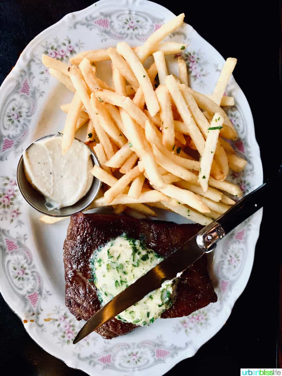 steak frites with a knife and side of butter on a formal china plate at La Moule restaurant in Portland, Oregon.