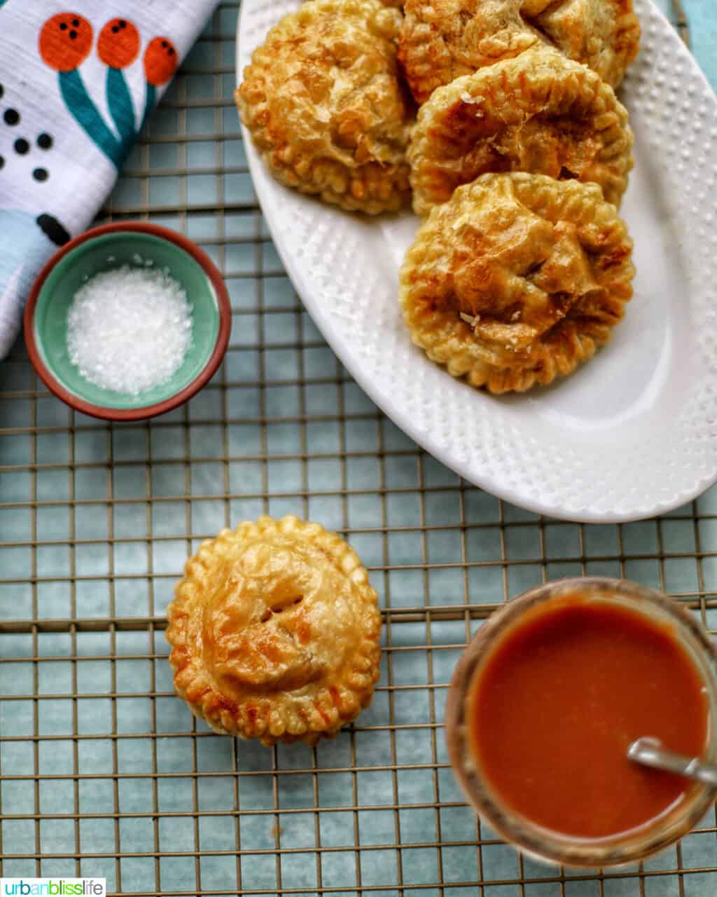 Air fryer apple hand pies on a rack with sanding sugar and caramel