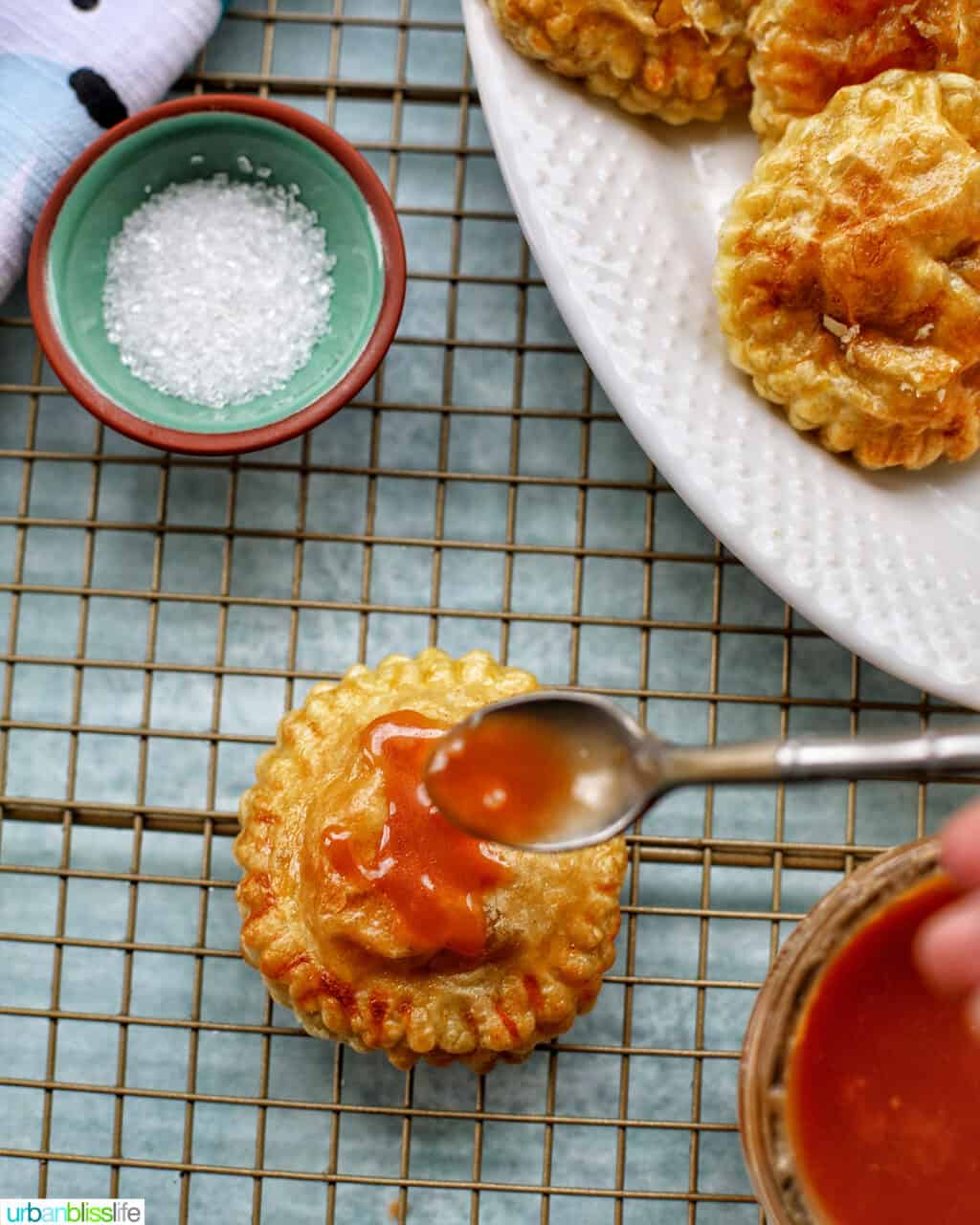 Air fryer apple hand pies on a rack with sanding sugar and caramel