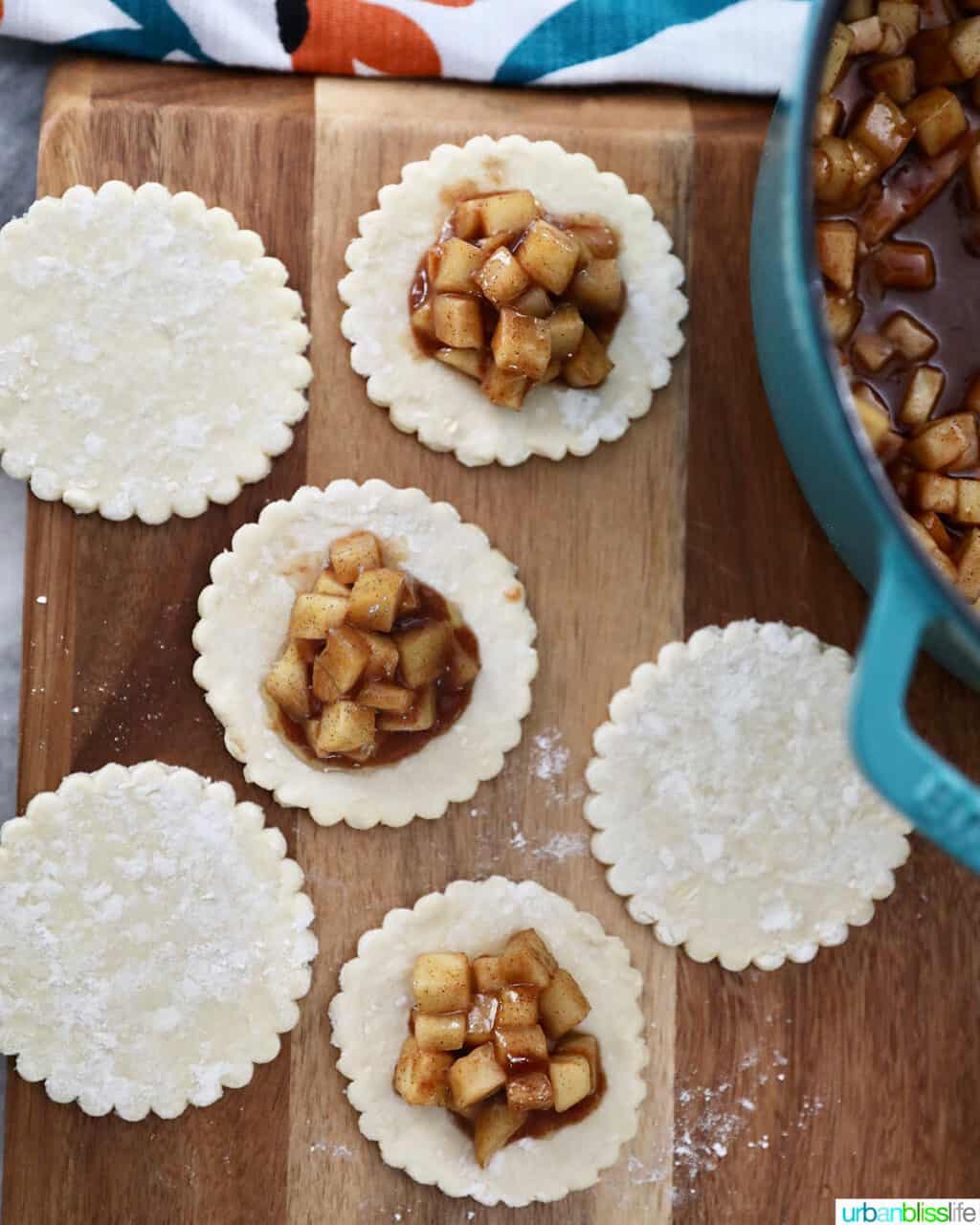 placing filling on top of dough rounds to make Air fryer apple hand pies on a rack with sanding sugar and caramel