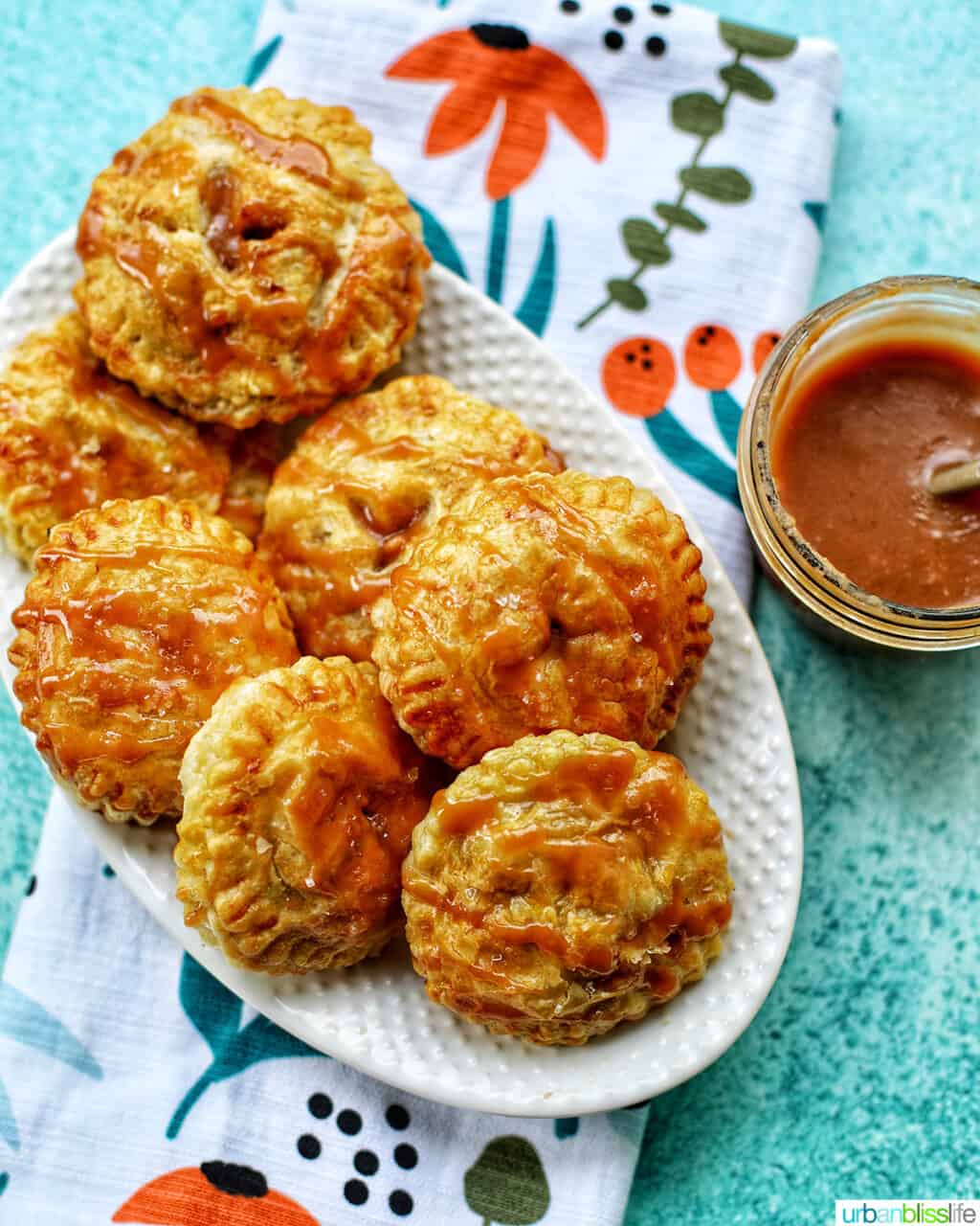 Air fryer apple hand pies on plate with bowl of caramel