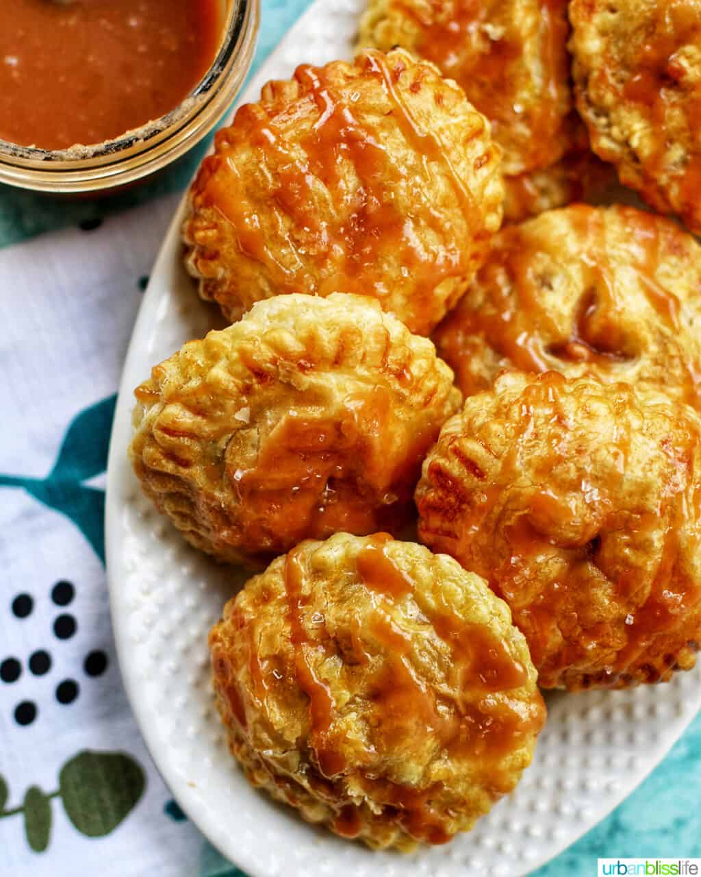Air fryer apple hand pies on plate with caramel sauce in corner