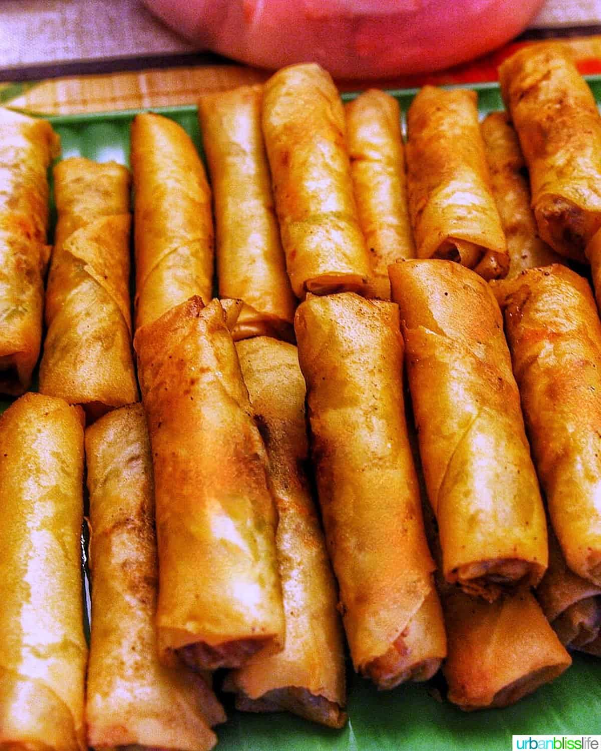 Tray of several stacked Filipino lumpia, egg rolls.