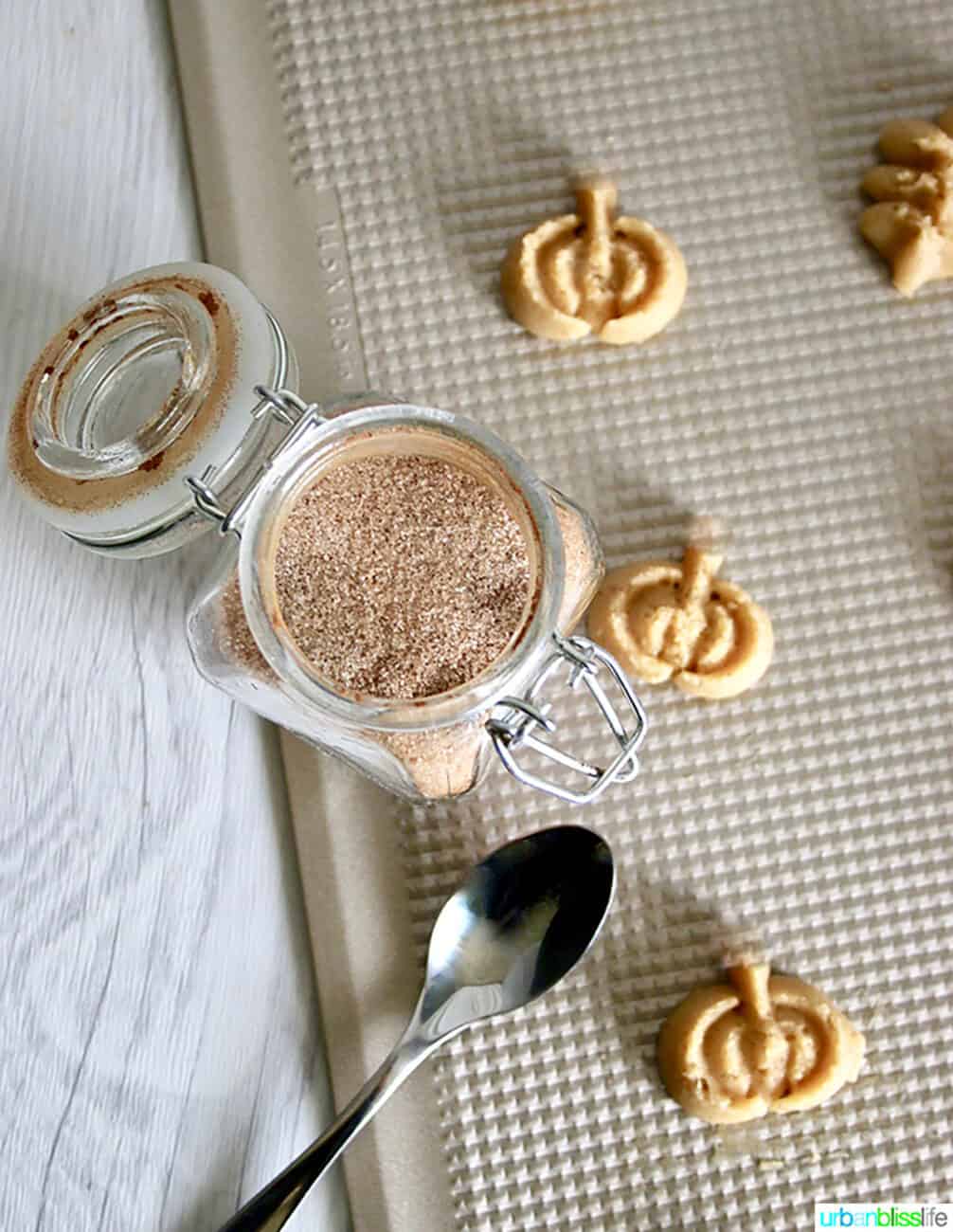 Spritz Cookies on a baking sheet with jar of cinnamon sugar