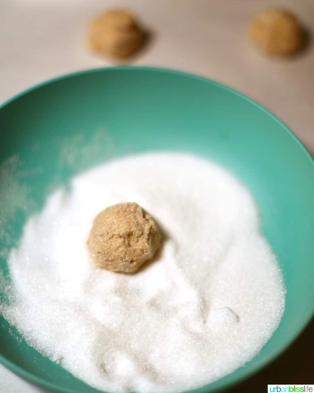 rolling peanut butter blossom cookies in sugar