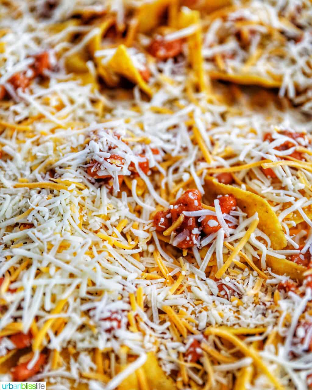 adding cheese to beans and chips for vegetarian nachos