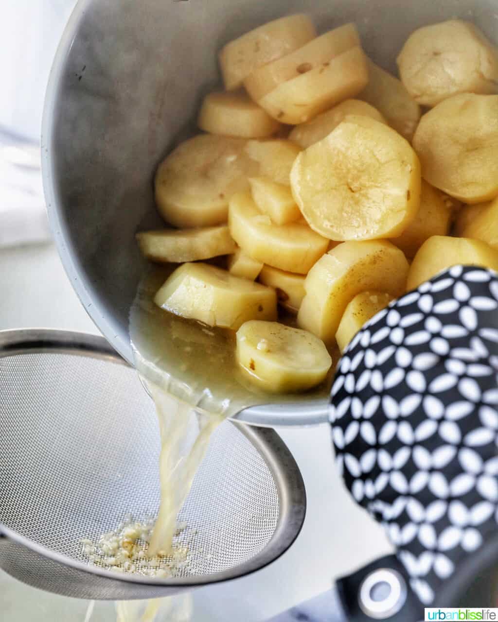 draining potatoes and garlic over a strainer