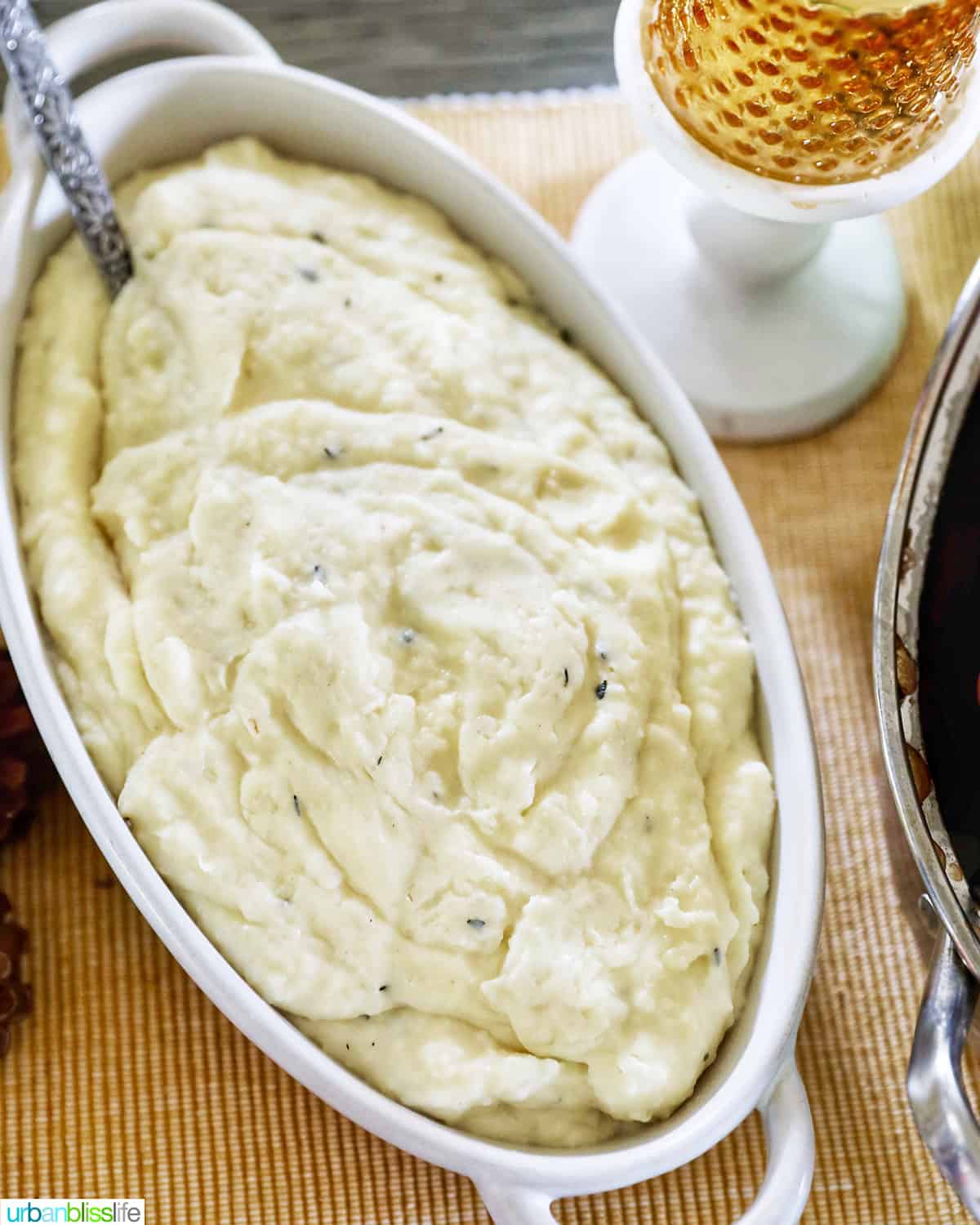 instant pot garlic mashed potatoes in serving bowl with a spoon and candle on the side.