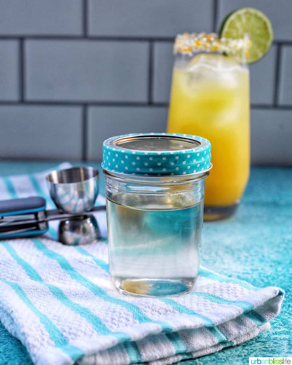 jar of simple syrup with cocktail in background