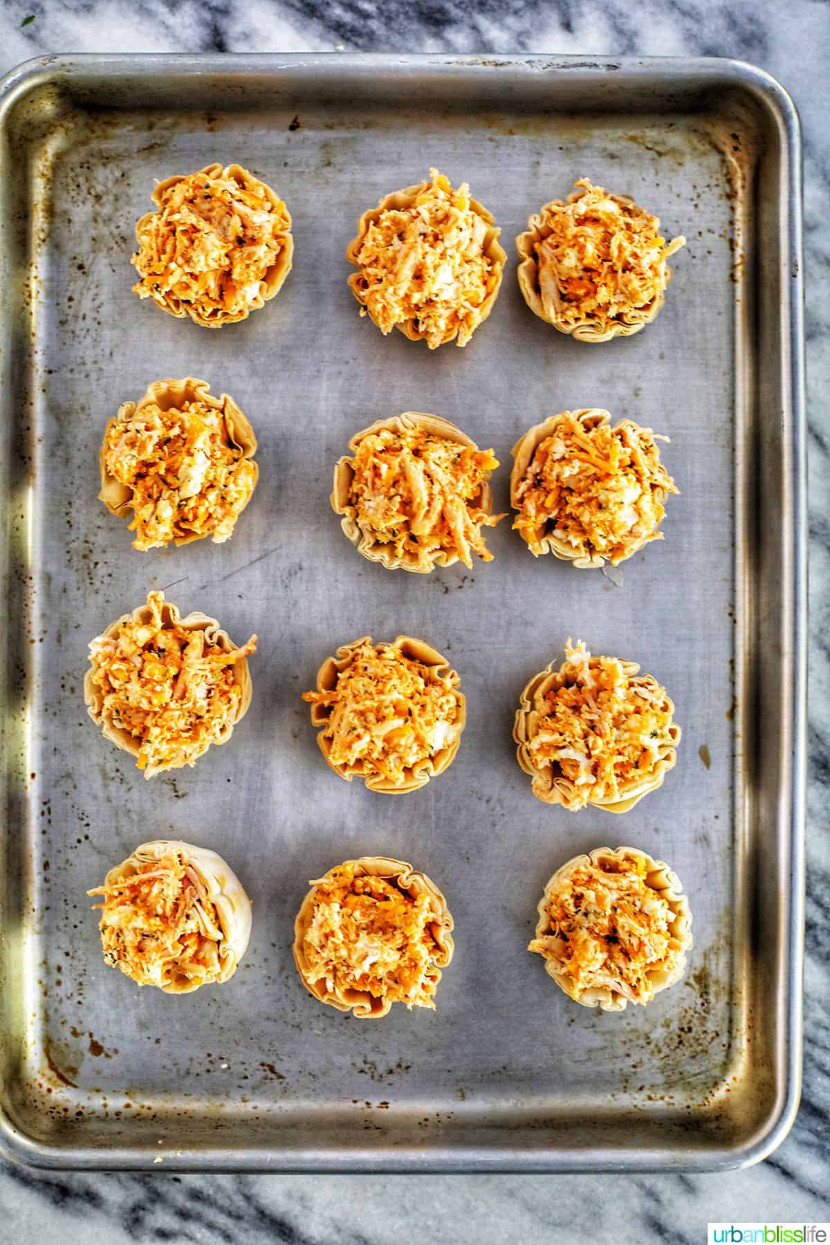 one dozen buffalo chicken bites on sheet pan ready to bake.