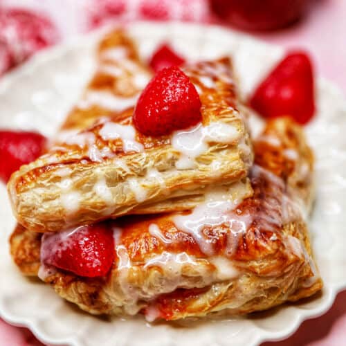 iced air fryer strawberry turnovers stacked on a plate with strawberries