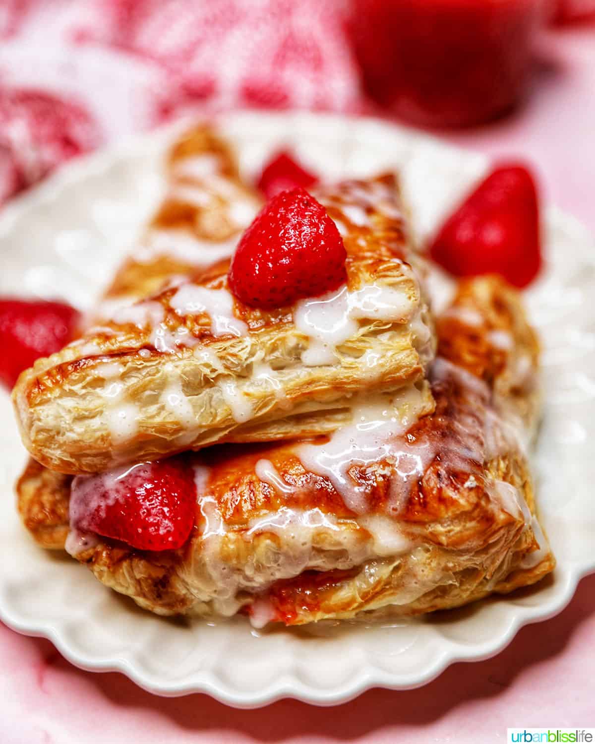 iced strawberry turnovers stacked on a plate with strawberries