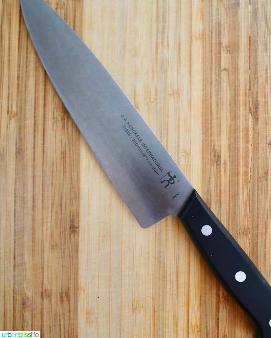 types of kitchen knives - henckels chefs knife on a wooden cutting board