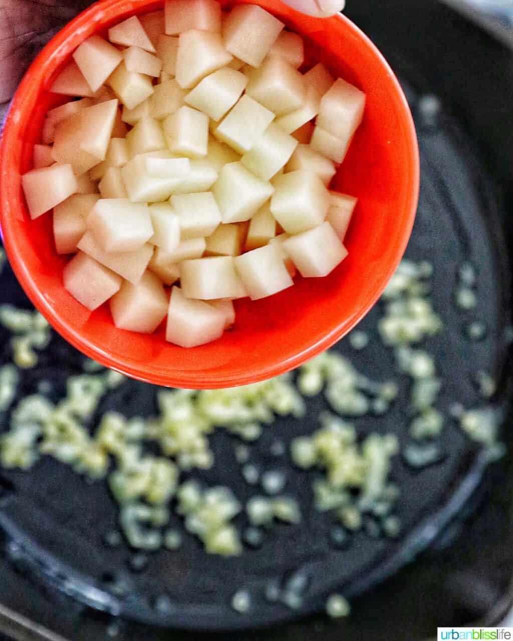 adding potatoes to pan