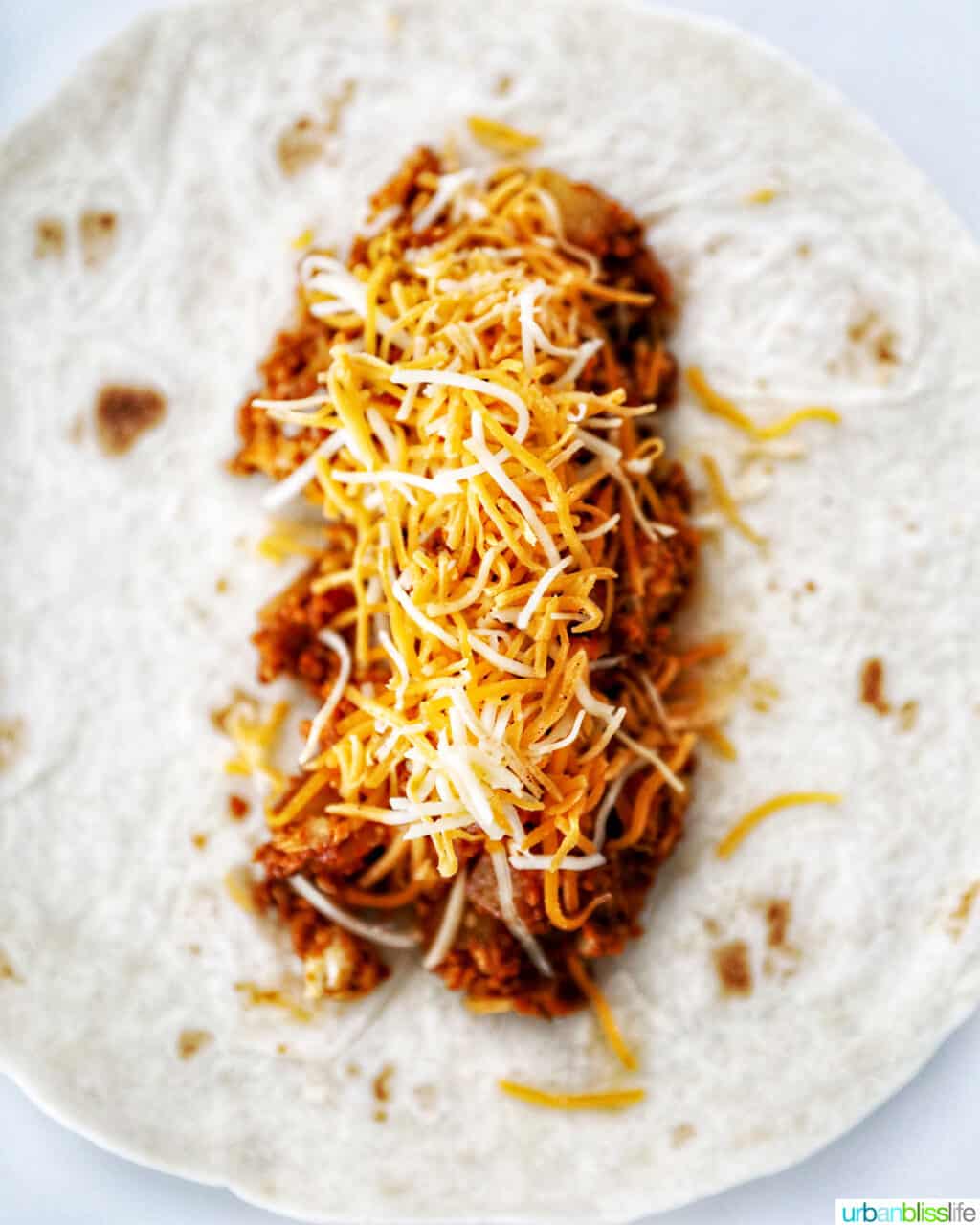 adding cheese to chorizo breakfast burrito