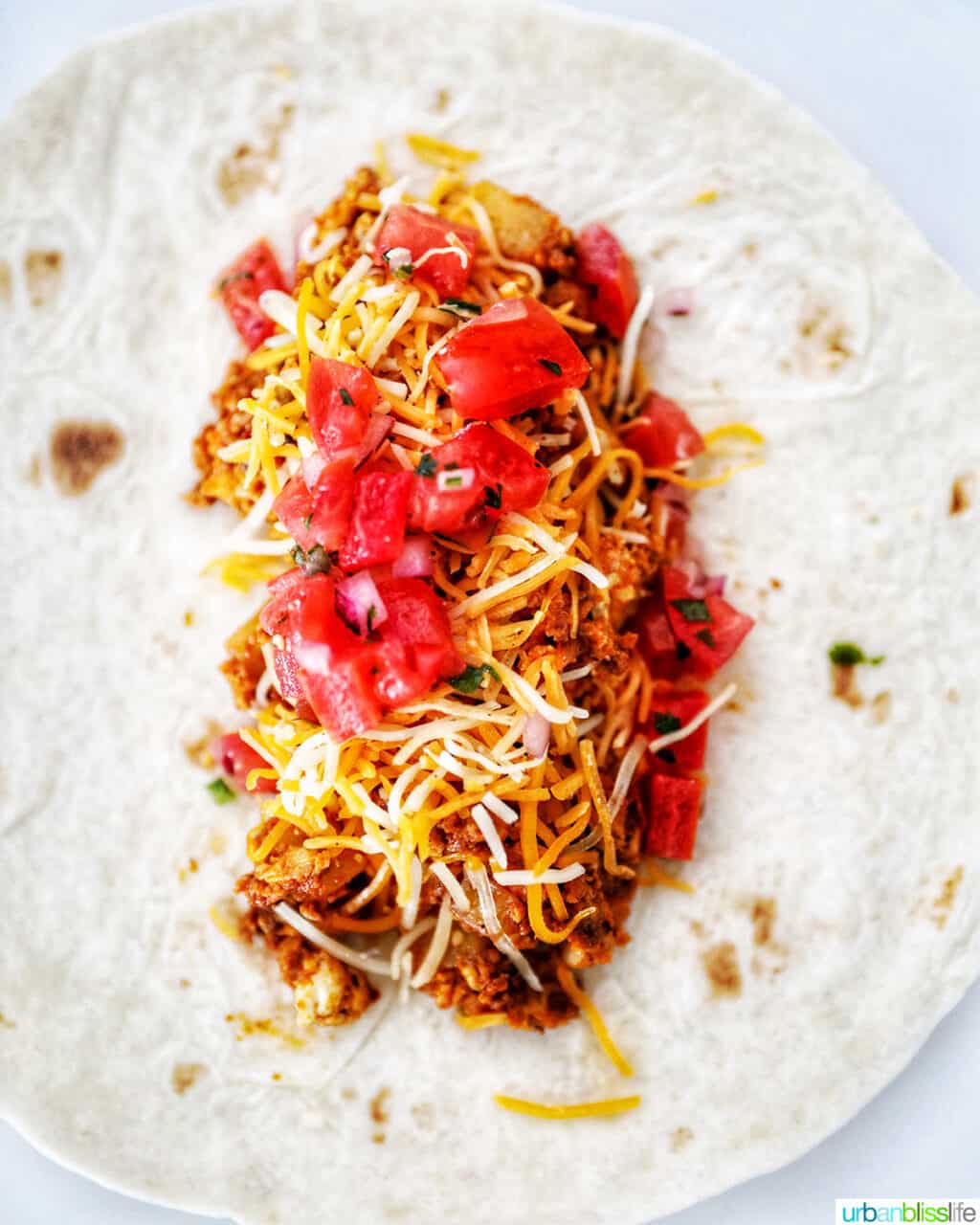 adding tomatoes to chorizo breakfast burrito