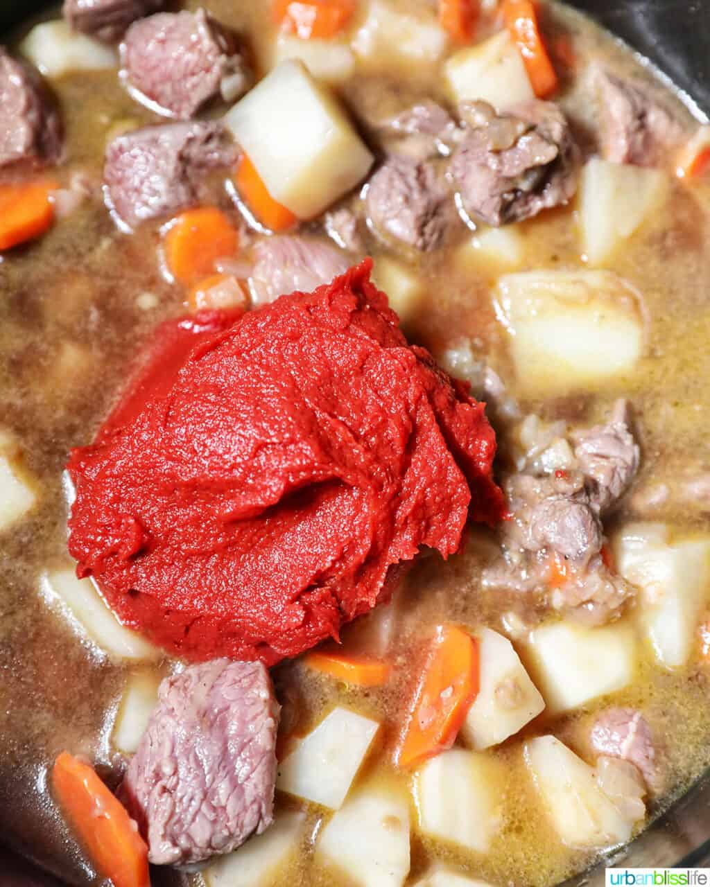 adding tomato paste to beef caldereta