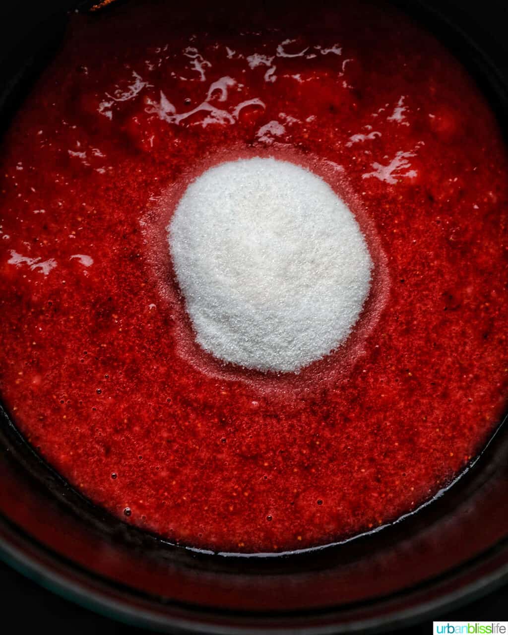 adding sugar to strawberries in pot